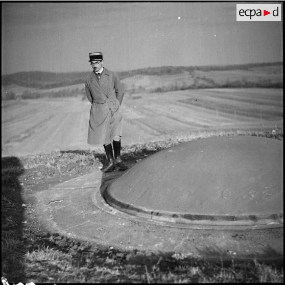 Un officier français est photographié en pied près d'une tourelle de 75 mm de l'ouvrage du Mont des Welches.