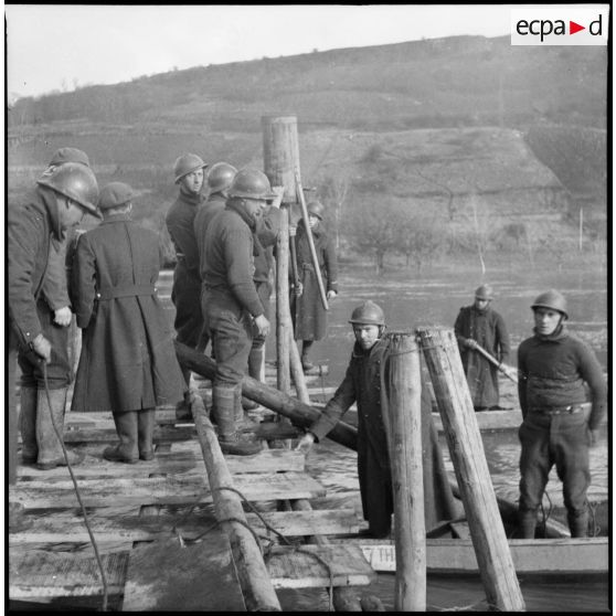 Des sapeurs du génie de la 3e armée construisent une passerelle de bois sur la Moselle.