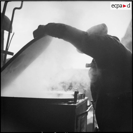 Un cuisinier du 80e RI soulève le couvercle d'une cuisine roulante.