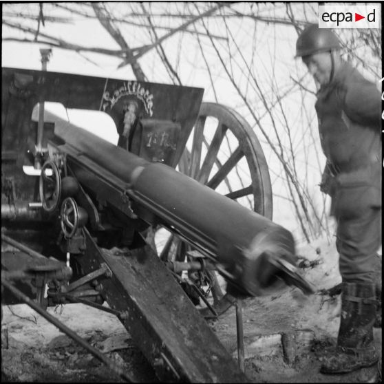 Plan moyen de trois quarts dos d'un tube de 75 mm M1897 de la 3e armée qui recule après un tir.