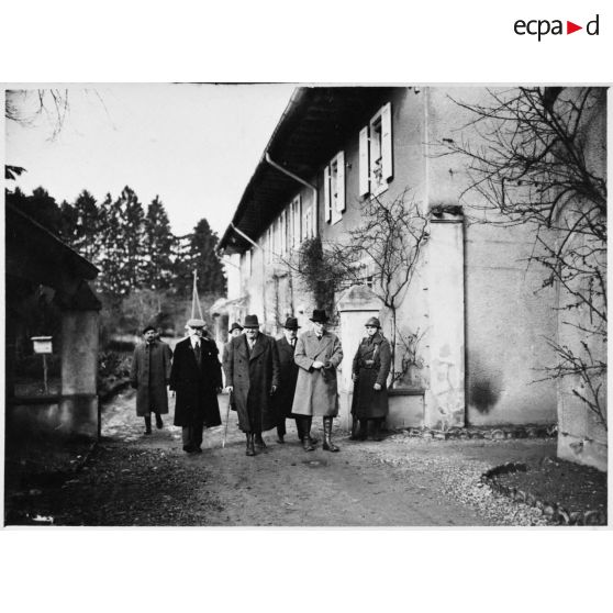 Photographie de groupe des personnalités politiques qui marchent près d'une maison.