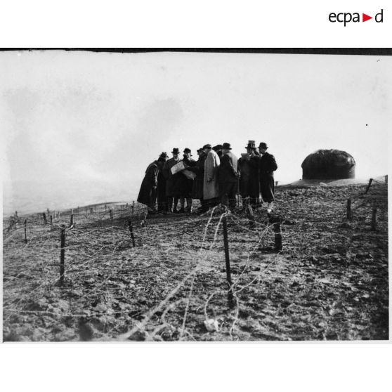 Photographie de groupe des personnalités politiques près d'une cloche métallique.