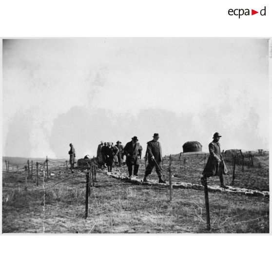 Photographie de groupe des personnalités politiques qui marchent près d'une maison.