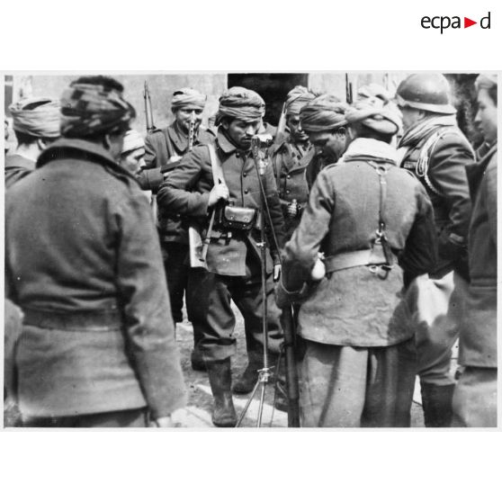Des soldats de la 3e armée originaires d'Afrique du nord entourent un micro dans un village de Moselle.