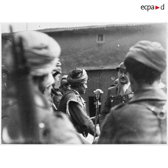 Des soldats de la 3e armée originaires d'Afrique du nord entourent un micro dans un village de Moselle.