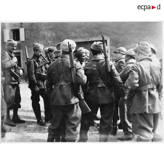 Des soldats de la 3e armée originaires d'Afrique du nord entourent un micro dans un village de Moselle.