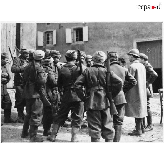 Des soldats de la 3e armée originaires d'Afrique du nord entourent un micro dans un village de Moselle.