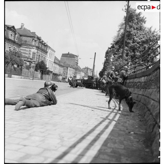 Dans une rue de Esch-sur-Alzette des soldats de la 3e DLC sont postés derrière un muret.