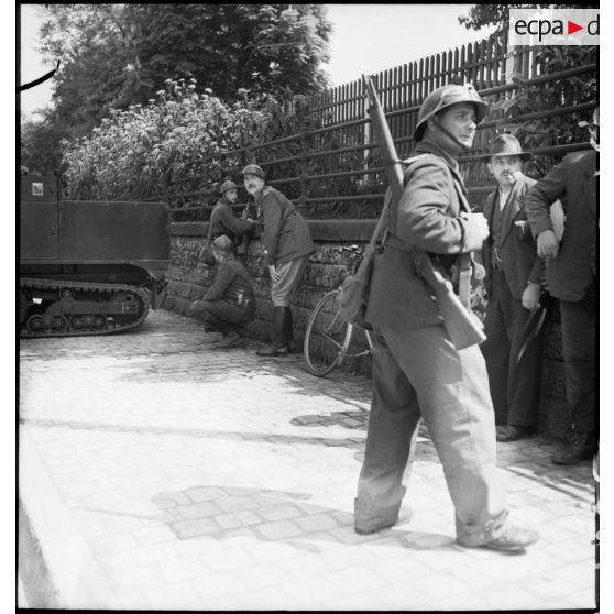 Dans une rue de Esch-sur-Alzette des soldats de la 3e DLC sont postés derrière un muret.