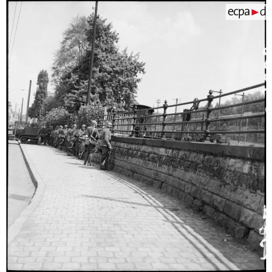 Dans une rue de Esch-sur-Alzette des soldats de la 3e DLC sont postés derrière un muret.