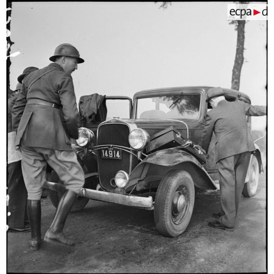 Un soldat de la 3e armée se tient devant une voiture civile luxembourgeoise à l'arrêt.