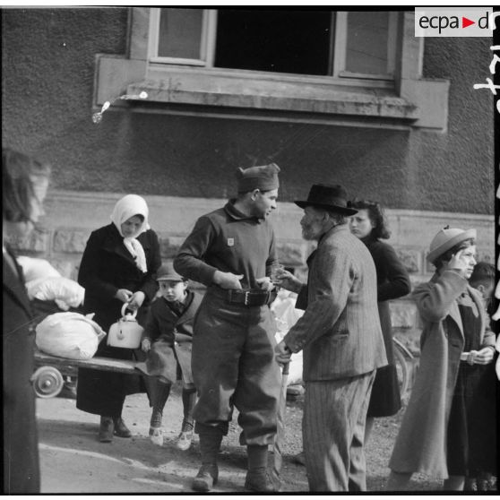 Photographie de groupe de réfugiés et d'un soldat de la 3e armée.
