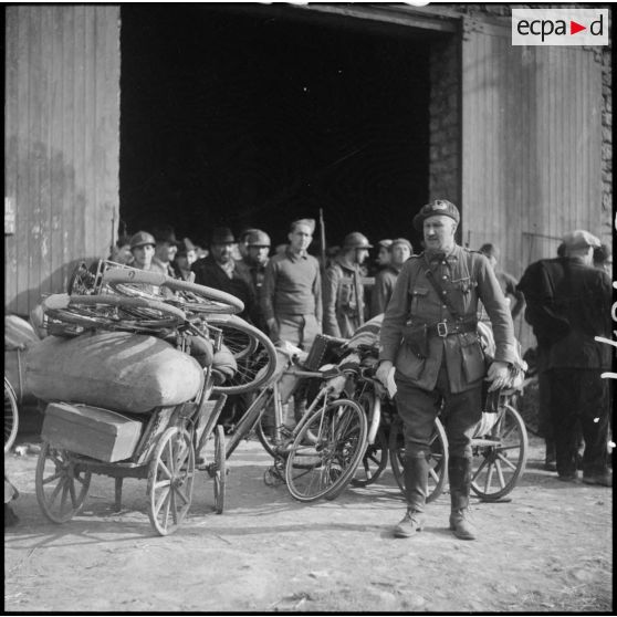 Un capitaine du 149e RIF est photographié en pied devant un hangar.