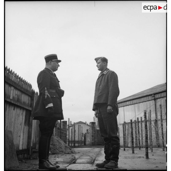Dehors, un gendarme français discute avec un prisonnier allemand.