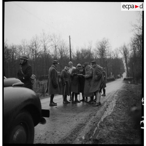 Des officiers généraux, dont les généraux Georges et Réquin, font un point de situation sur le bord d'une route.
