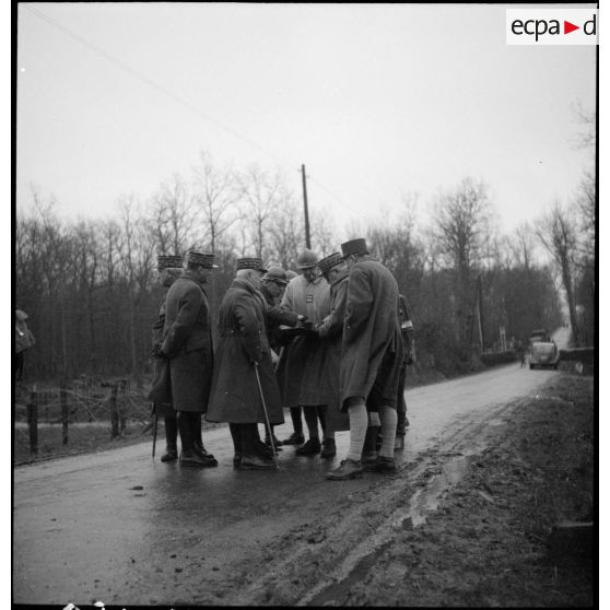 Des officiers généraux, dont les généraux Georges et Réquin, font un point de situation sur le bord d'une route.