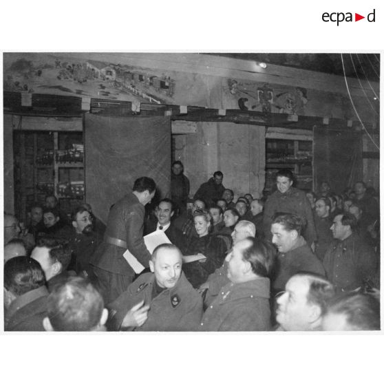 Danielle Darrieux est assise dans une salle de spectacle au milieu de soldats de la 4e armée.