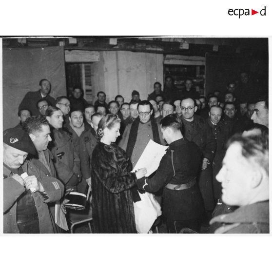 Danielle Darrieux signe des autographes dans une salle de spectacle pour des soldats de la 4e armée.