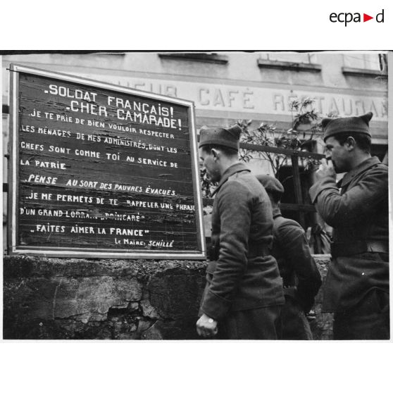 Des soldats de la 4e armée lisent une affiche demandant de respecter les biens civils d'un village lorrain évacué.