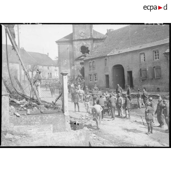 Dans une rue de village des soldats de la 4e armée poussent une pompe à bras.