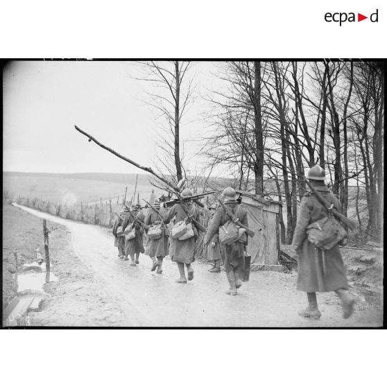 Des fantassins d'une section de mitrailleuses marchent sur une route dans le secteur de la 4e armée.