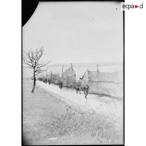 Des fantassins d'une section de mitrailleuses marchent sur une route dans le secteur de la 4e armée.