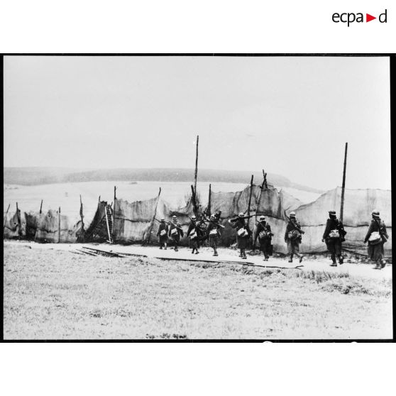 Des fantassins d'une section de mitrailleuses marchent sur une route dans le secteur de la 4e armée.