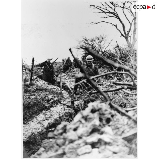Des fantassins d'une section de mitrailleuses marchent dans un boyau dans le secteur de la 4e armée.
