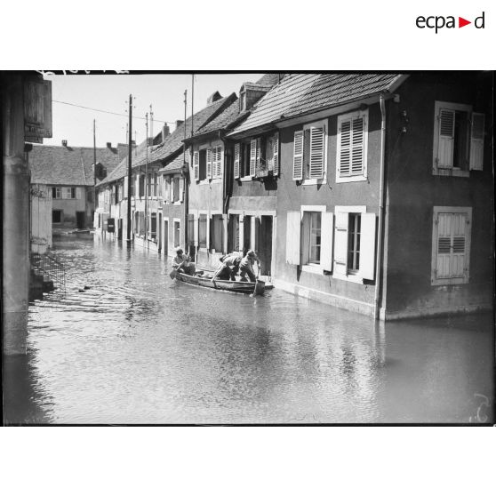 Des soldats de la 4e armée se déplacent en barque au milieu d'un village lorrain inondé. (Puttelange-aux-Lacs).