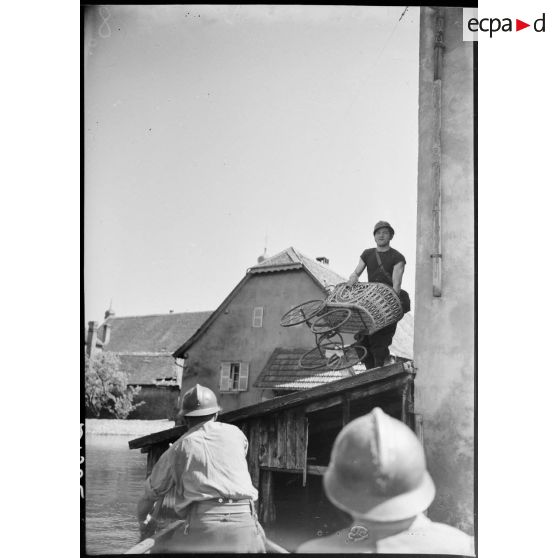 Des soldats de la 4e armée déménagent des affaires dans une barque lors de l'inondation d'un village. (Puttelange-aux-Lacs).