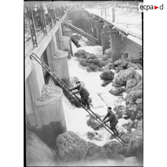 Deux soldats de la 4e armée montent sur une échelle posée près d'une cascade.
