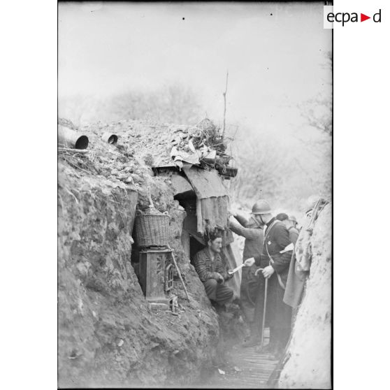 Dans une tranchée un aumônier en visite donne une lettre à un soldat de la 4e armée.