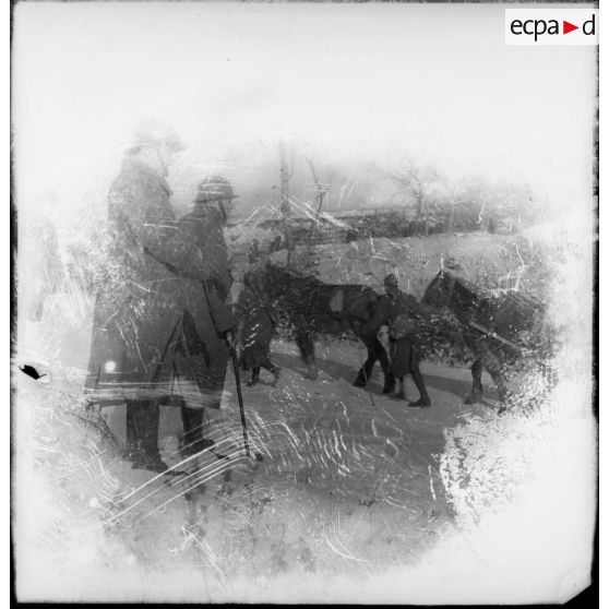 Un officier de la 4e armée regarde passer un convoi de ravitaillement dans la neige.