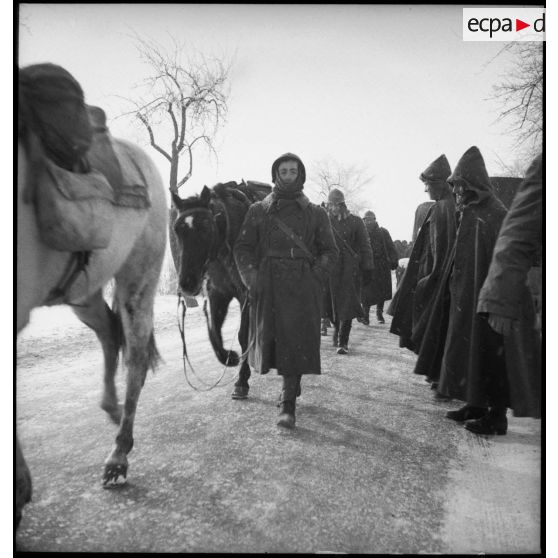 Un soldat de la 4e armée est photographié en pied alors qu'il accompagne une colonne de mulets sous la neige.