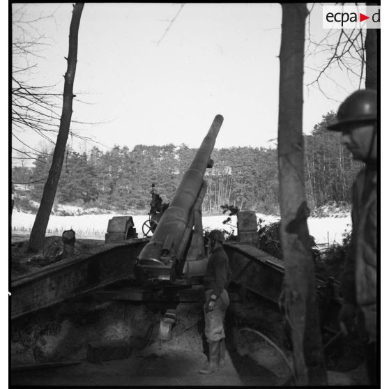 Une pièce de 155 mm GPF de la 5e armée, mise en batterie à la lisère d'un bois, est photographiée de dos.