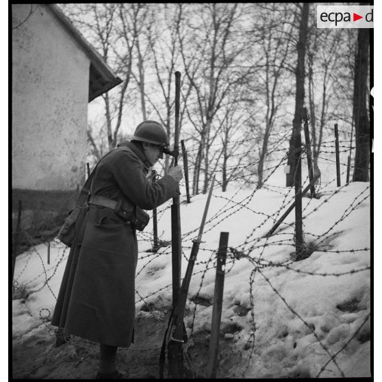 Une sentinelle de la 5e armée est photographiée près de barbelés enneigés.