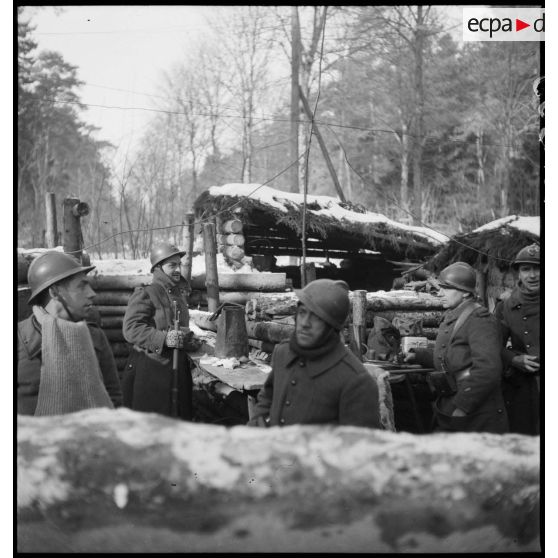 Photographie de groupe de soldats de la 5e armée en poste dans un abri de rondins.