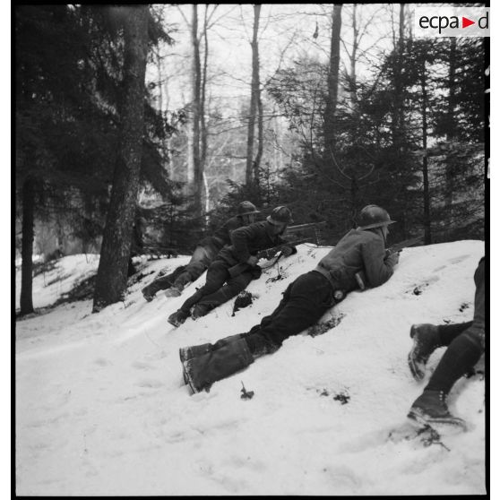 Des soldats de la 5e armée en patrouille sont postés dans un fossé enneigé d'un bois.