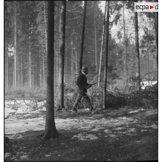 Des soldats de la 5e armée marchent en patrouille dans un bois enneigé.