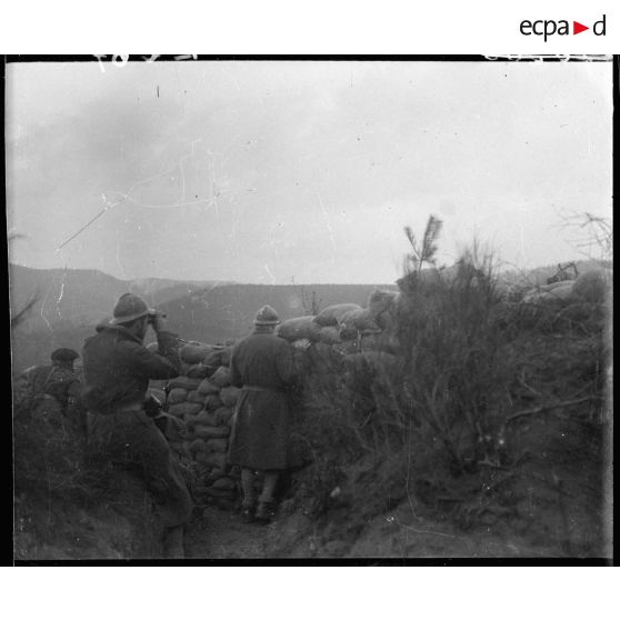 Des soldats de la 5e armée observent le paysage derrière des sacs de sable.