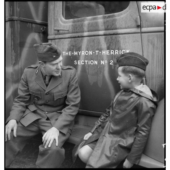 L'ambulancier américain George Emerson Cox de la Section sanitaire de volontaires américains n° 2 (SSVA n°2) est assis sur le marchepied d'une ambulance Chevrolet en compagnie d'un enfant.