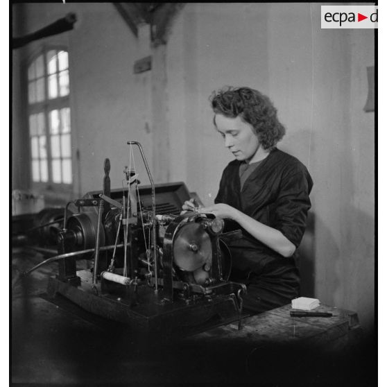 Dans un atelier une ouvrière travaille à la fabrication de piles électriques.