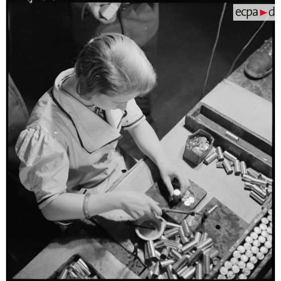 Dans un atelier une ouvrière travaille à la fabrication de piles électriques.
