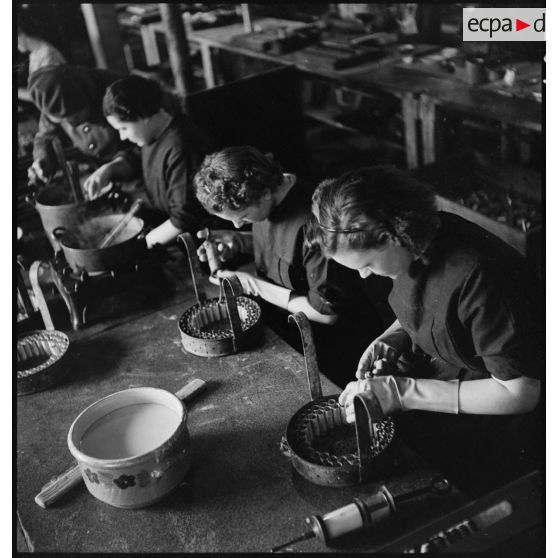Dans un atelier des ouvrières travaillent à la fabrication de piles électriques.