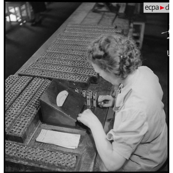 Dans un atelier une ouvrière travaille à la fabrication de piles électriques.