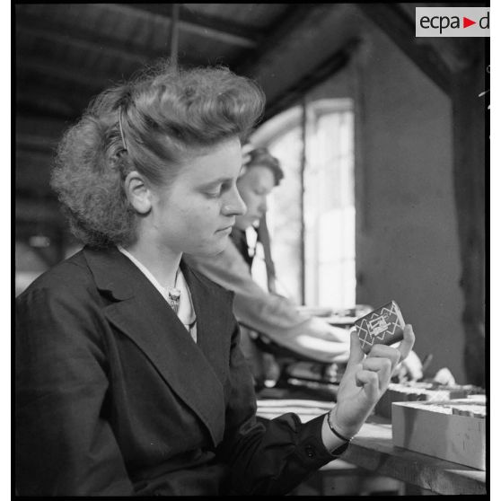 Dans un atelier une ouvrière travaille à la fabrication de piles électriques.