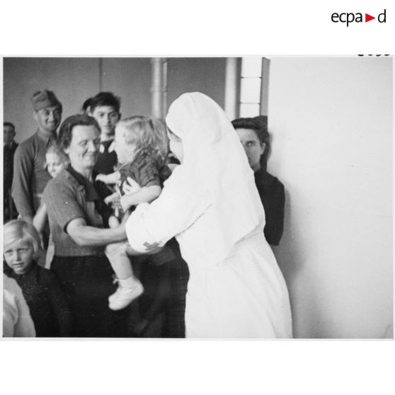 Une femme tend les bras pour donner son enfant à une infirmière dans un hôpital du secteur de la 5e armée.