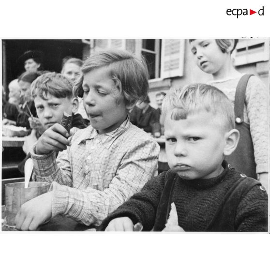 Portrait d'enfants réfugiés qui mangent dans une cour d'école.