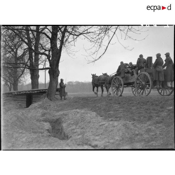 Une cuisine roulante et son équipage passe devant une sentinelle en poste au bord d'une route près d'un abri.