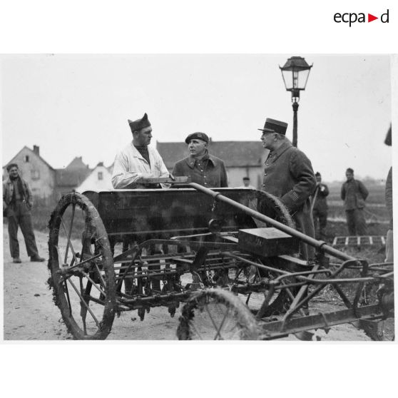 Deux officiers de la 5e armée sont photographiés devant une machine agricole.